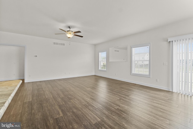 unfurnished living room featuring ceiling fan, visible vents, dark wood-style floors, and baseboards