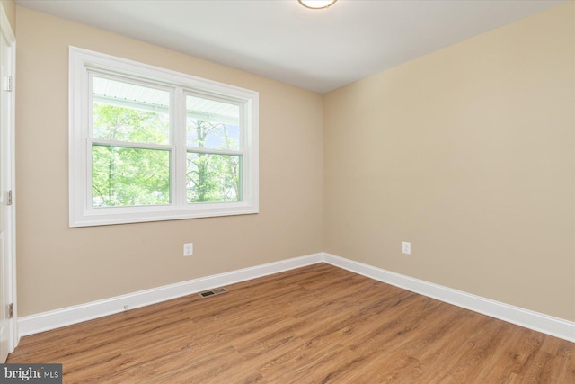 spare room featuring baseboards, light wood-style flooring, and visible vents