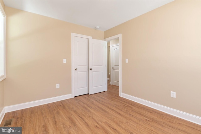 unfurnished bedroom featuring baseboards, visible vents, and light wood-style flooring