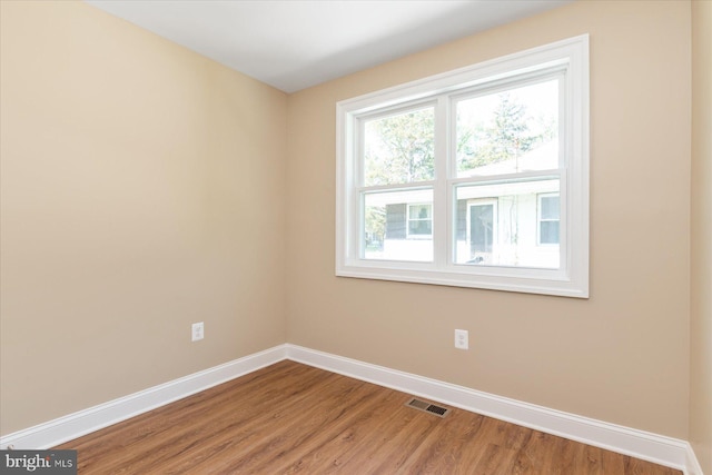 spare room with visible vents, baseboards, and wood finished floors