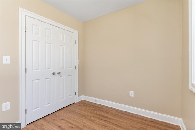 unfurnished bedroom with baseboards, light wood finished floors, and a closet