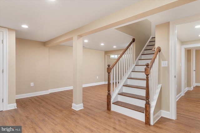 finished below grade area with light wood-style floors, baseboards, stairway, and recessed lighting