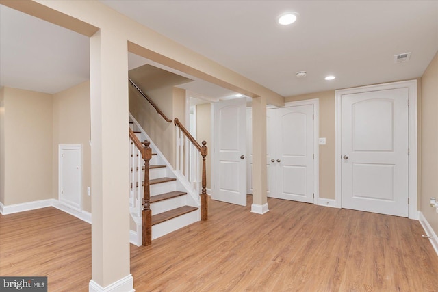 below grade area with recessed lighting, baseboards, light wood-type flooring, visible vents, and stairway