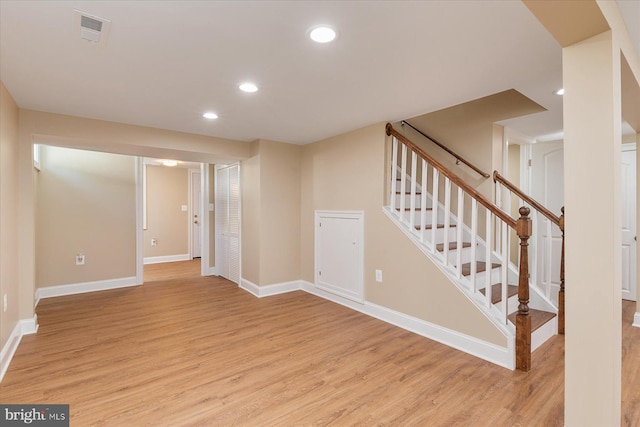 finished below grade area featuring light wood-style floors, recessed lighting, baseboards, visible vents, and stairway