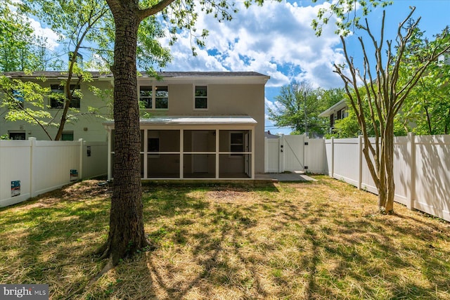 rear view of property featuring a gate, a sunroom, a fenced backyard, a yard, and stucco siding
