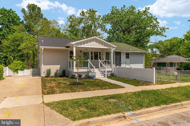 view of front facade with fence, board and batten siding, a front yard, a gate, and covered porch