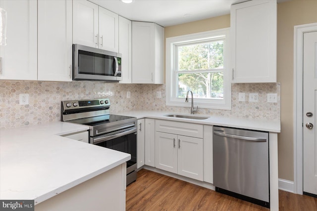 kitchen with wood finished floors, light countertops, white cabinetry, a sink, and appliances with stainless steel finishes