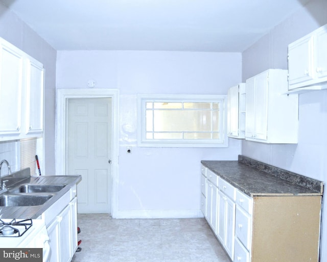 90 E State St, Camden, NJ 08105 - kitchen featuring dark countertops, white cabinets, a sink, white gas stove, and decorative backsplash