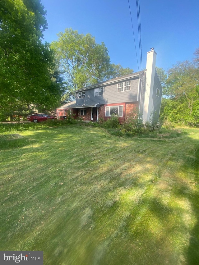 rear view of house with a lawn and a chimney
