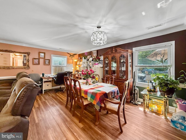 dining room with visible vents, light wood-style floors, and crown molding