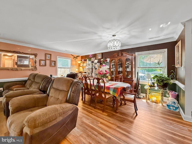 dining space featuring a chandelier, visible vents, ornamental molding, and light wood finished floors