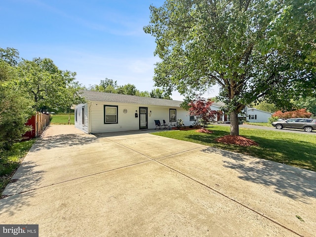 ranch-style house featuring a front lawn, fence, and driveway
