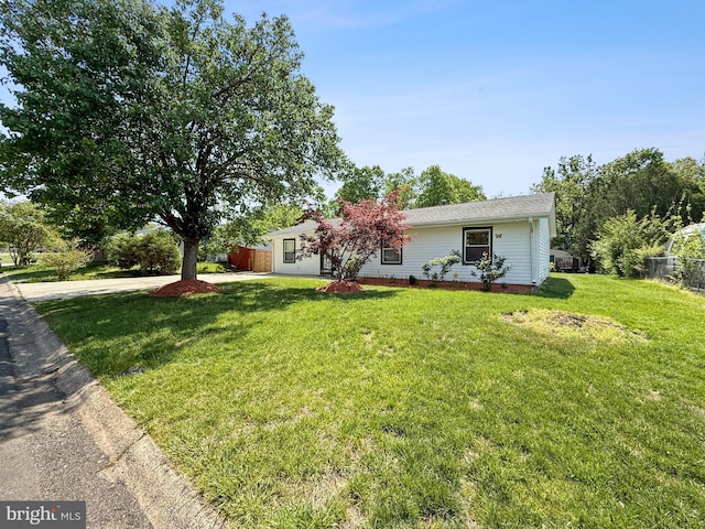 ranch-style home with an attached garage, fence, driveway, and a front yard