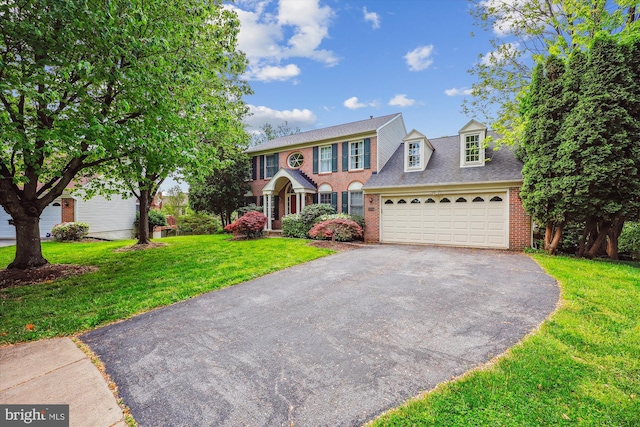 colonial house with brick siding, an attached garage, a front yard, and aphalt driveway
