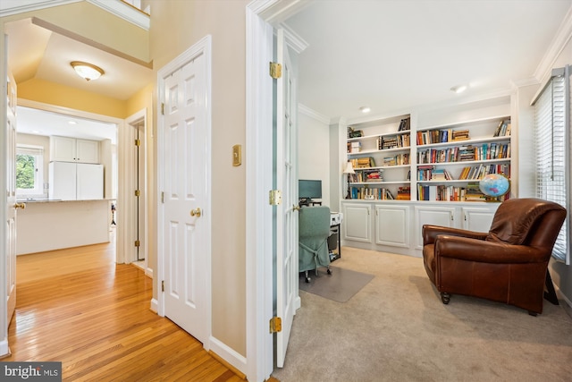 sitting room with ornamental molding and light wood-style flooring