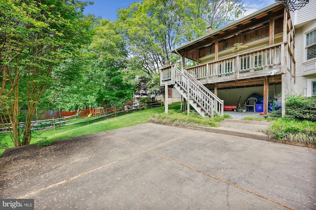 rear view of house featuring stairway, a patio, a wooden deck, and a lawn