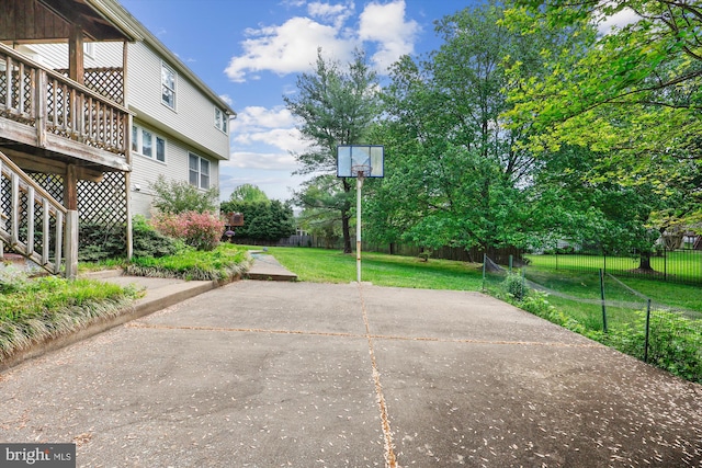 view of sport court with a lawn and fence