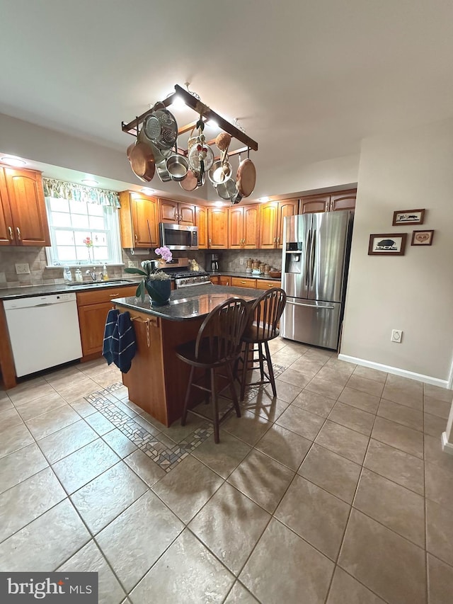 902 Hedgewyck Ln, Elizabethtown, PA 17022 - kitchen with appliances with stainless steel finishes, a kitchen island, light tile patterned floors, decorative backsplash, and a kitchen bar