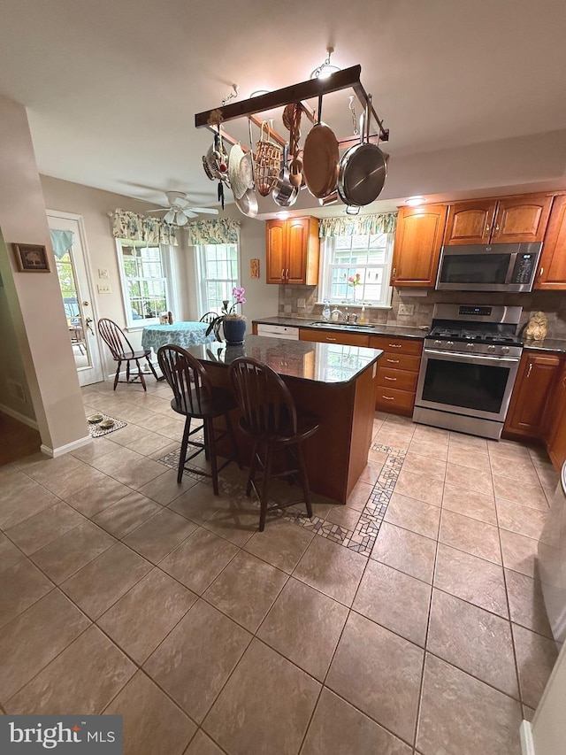 902 Hedgewyck Ln, Elizabethtown, PA 17022 - kitchen featuring appliances with stainless steel finishes, light tile patterned floors, tasteful backsplash, a kitchen breakfast bar, and brown cabinets