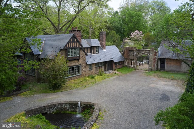 view of front of home featuring a chimney, a gate, asphalt driveway, and stone siding