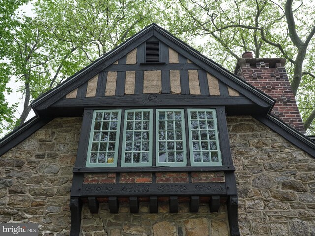 view of home's exterior with stone siding and a chimney