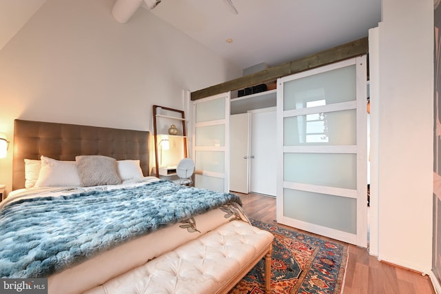 bedroom featuring wood finished floors and high vaulted ceiling