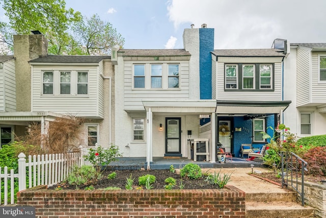 townhome / multi-family property featuring covered porch and fence