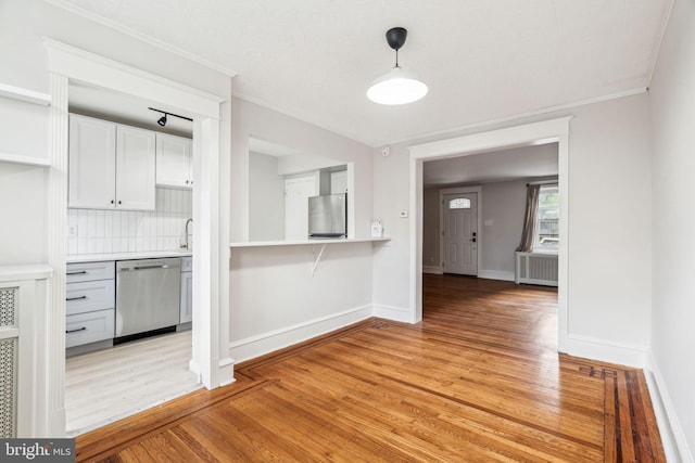 kitchen with stainless steel dishwasher, refrigerator, light wood-style flooring, light countertops, and ornamental molding