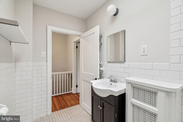bathroom with tile walls, tile patterned floors, wainscoting, and vanity