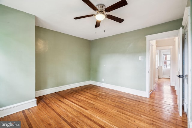 unfurnished room featuring a ceiling fan, light wood finished floors, and baseboards