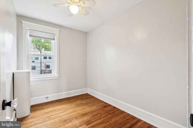 unfurnished room featuring baseboards, light wood finished floors, and a ceiling fan