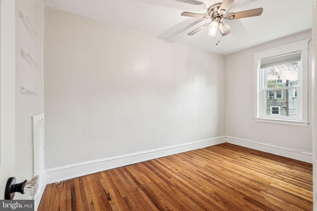 spare room with baseboards, wood finished floors, and ceiling fan
