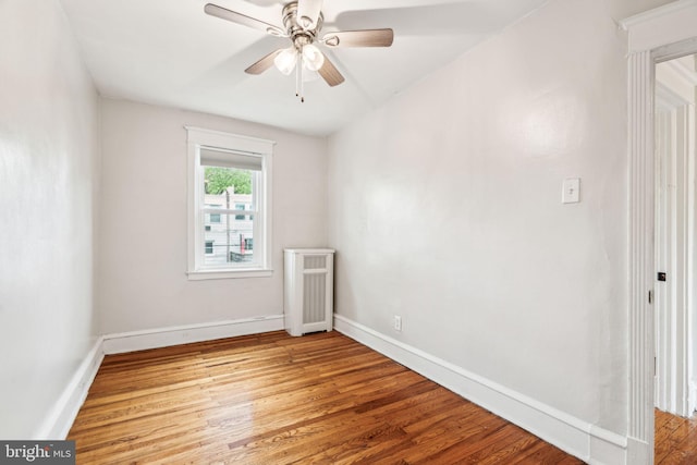 empty room featuring wood finished floors, baseboards, and a ceiling fan