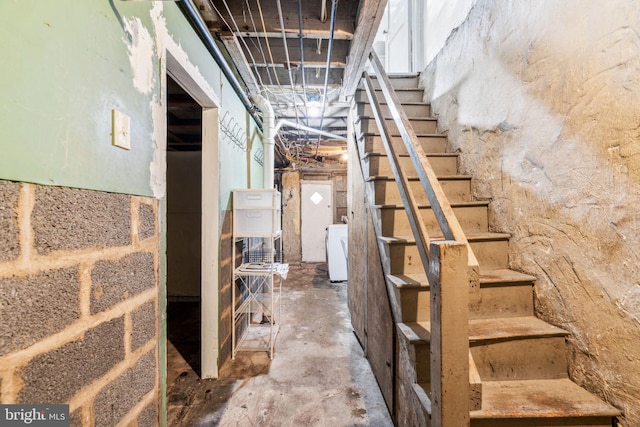 unfinished basement with stairs and washer / dryer