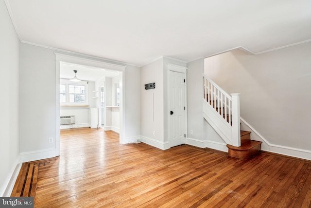 unfurnished living room featuring light wood finished floors, stairway, ornamental molding, baseboards, and a wall unit AC