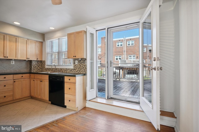 kitchen featuring light brown cabinetry, dark countertops, backsplash, and black dishwasher
