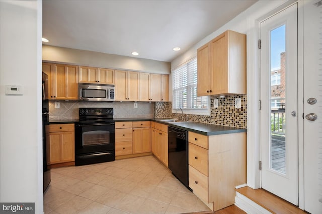 kitchen with a sink, dark countertops, black appliances, and light brown cabinets
