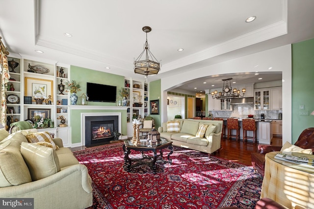 19326 Airwell Ct, Purcellville, VA 20132 - living room with a glass covered fireplace, dark wood-type flooring, a tray ceiling, arched walkways, and a notable chandelier