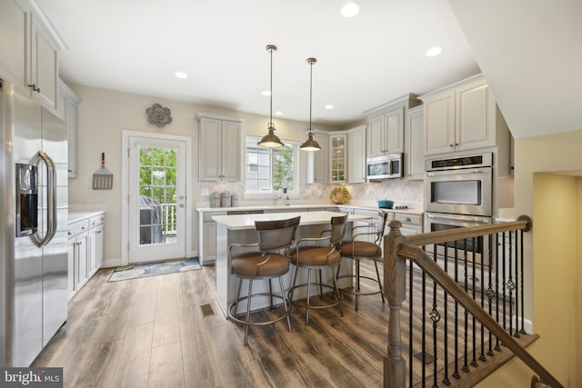 10723 Caledonia Meadow Dr, Manassas, VA 20112 - kitchen featuring stainless steel appliances, wood finished floors, light countertops, decorative backsplash, and a kitchen island