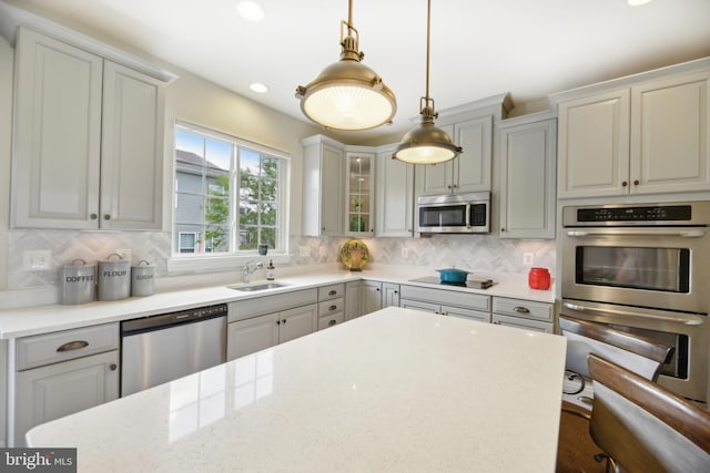 10723 Caledonia Meadow Dr, Manassas, VA 20112 - kitchen with appliances with stainless steel finishes, tasteful backsplash, pendant lighting, a sink, and glass insert cabinets