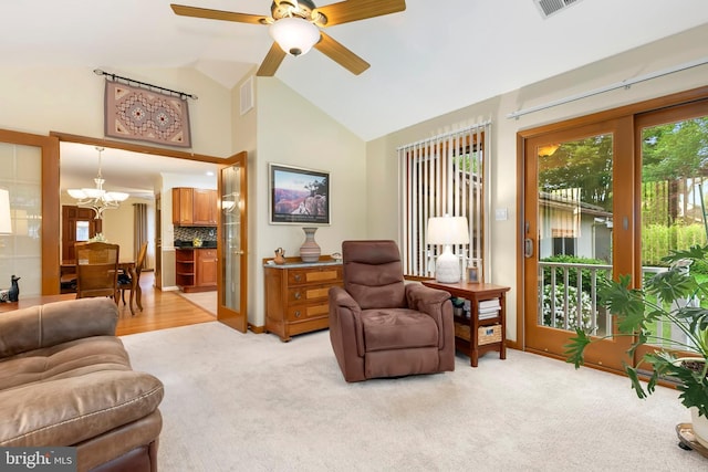 living room featuring vaulted ceiling, light colored carpet, ceiling fan with notable chandelier, and visible vents