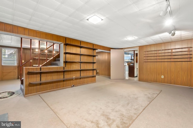 below grade area with wooden walls, carpet floors, and stairs
