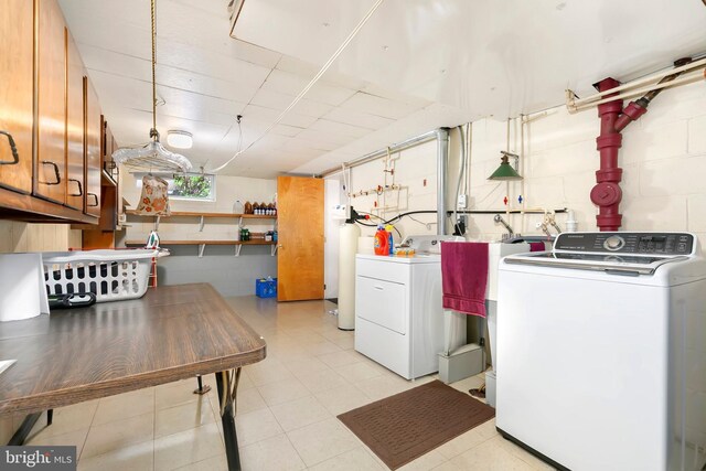 clothes washing area with separate washer and dryer, cabinet space, and concrete block wall