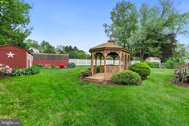 view of yard with an outdoor structure, fence, a gazebo, and a storage unit