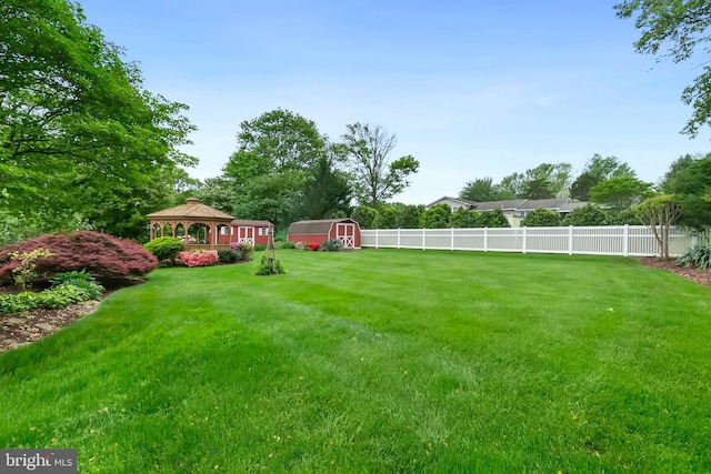 view of yard featuring an outdoor structure, a gazebo, a fenced backyard, and a shed