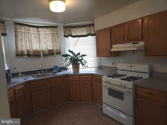 5737 N Park Ave, Philadelphia, PA 19141 - kitchen with white gas range oven, a sink, brown cabinetry, under cabinet range hood, and light countertops
