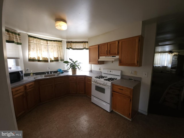 5737 N Park Ave, Philadelphia, PA 19141 - kitchen featuring under cabinet range hood, white gas range, a sink, black microwave, and brown cabinets