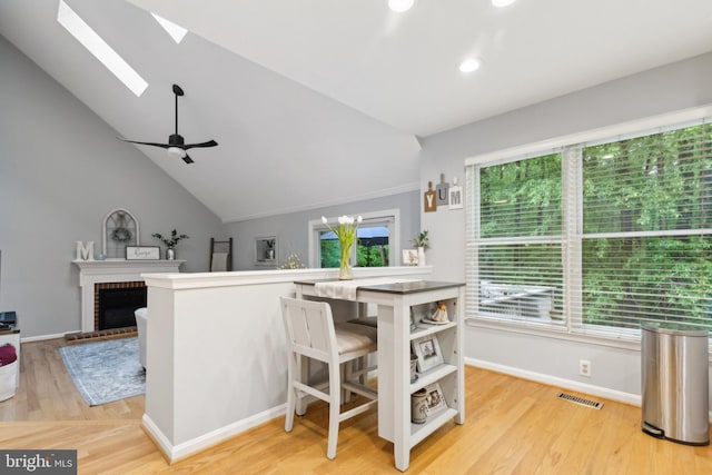 6724 Passageway Pl, Burke, VA 22015 - kitchen featuring a skylight, light wood-style flooring, open shelves, vaulted ceiling, and baseboards