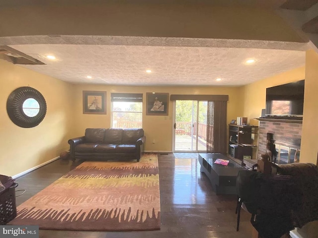 living area featuring baseboards, a textured ceiling, and a fireplace