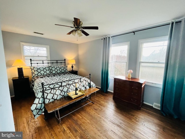 bedroom featuring multiple windows, wood finished floors, baseboards, and ceiling fan